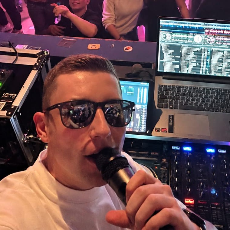 DJ Luca Bluhm mit Mikrofon hinter seinem DJ-Pult