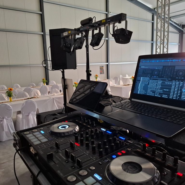 DJ-Pult mit Pioneer DDJ SX2 Controller, Laptop, Lautsprecher und Lichtbar in einer festlich gedeckten Halle